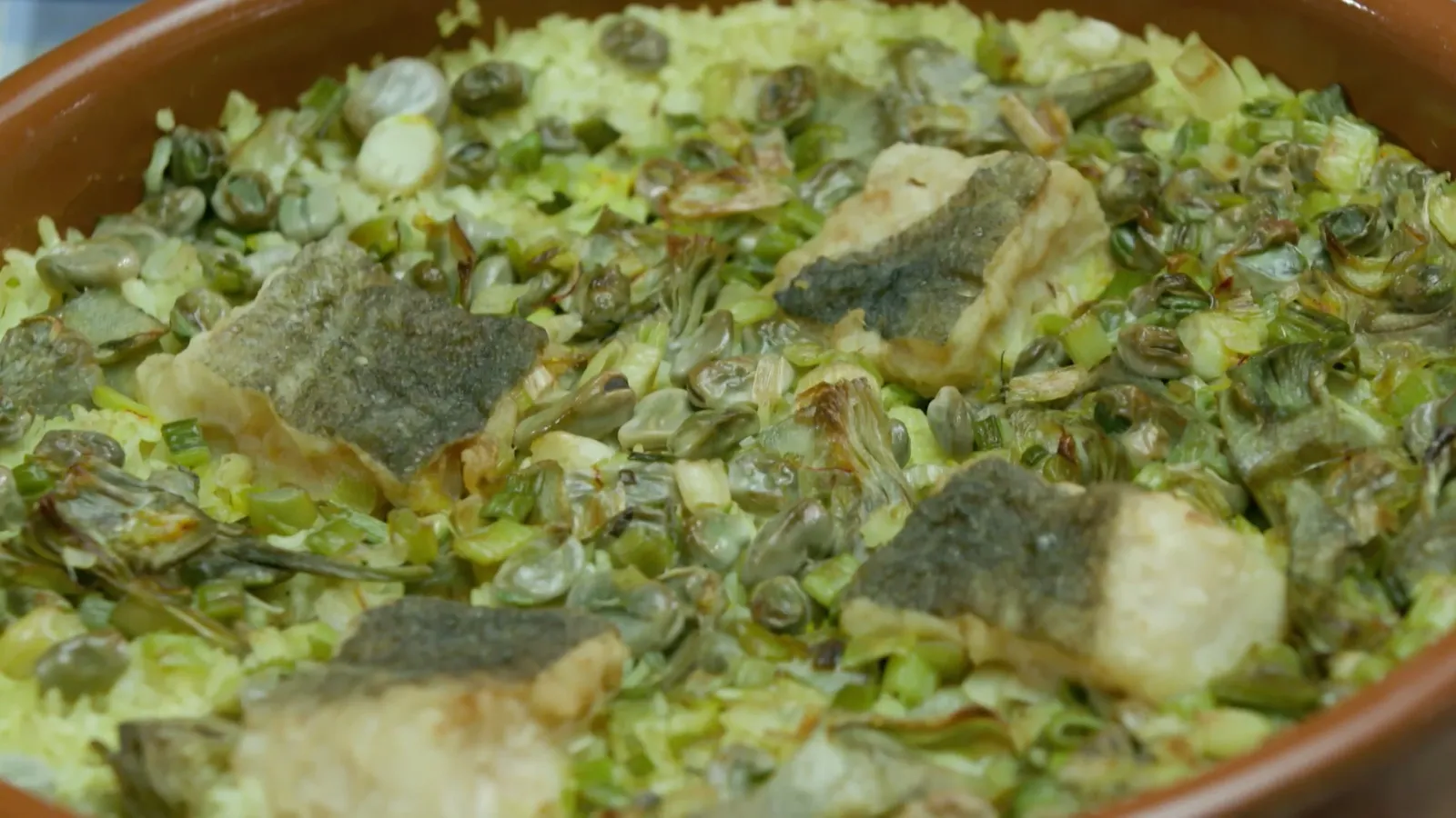 Cassola de Quaresma recien horneada con el arroz las alcachofas y el bacalao dorados en una fuente de barro tradicional