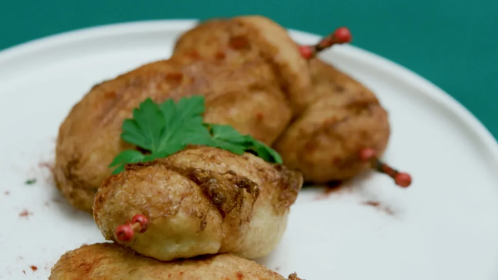 Un plato lleno de ximos dorados y crujientes cortados por la mitad mostrando su jugoso relleno de atun tomate y huevo duro